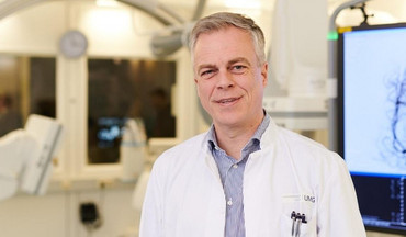  Univ.-Prof. Dr. Christian Riedel steht vor einer Flachdetektor-Angiographieanlage