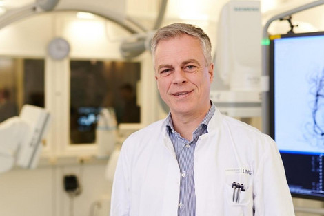 Prof. Dr. Christian Riedel steht vor einem Flachdetektor CT